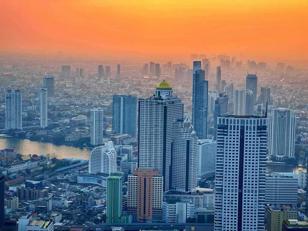 Blick beim Sonnenuntergang von der Aussichtsplattform des Maha Nakhon Tower / King Power Mahanakhon auf Bangkok mit der goldenen Kuppel der Sky Bar des Lebua State Tower