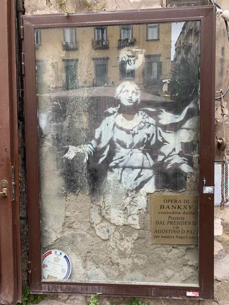 Neapel ist stolz auf sein Mural von Banksy an der Piazza Girolamini (Via Tribunale) und hat es sicherheitshalber durch Glas geschützt © PetersTravel Peter Pohle